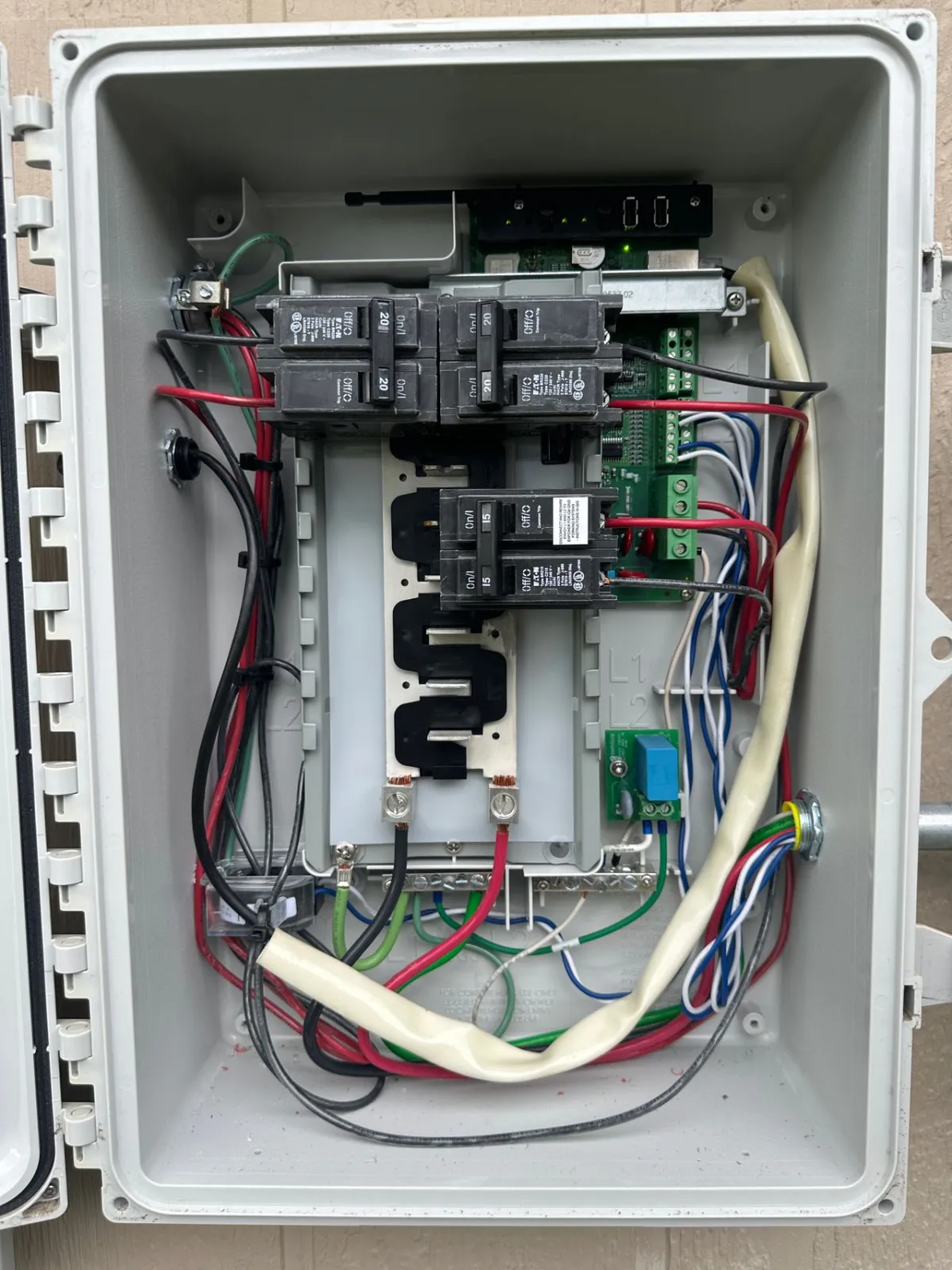 Inside the Enphase combiner panel with the cover open, showing the breakers, wiring, and the terminal landings Josh inspected